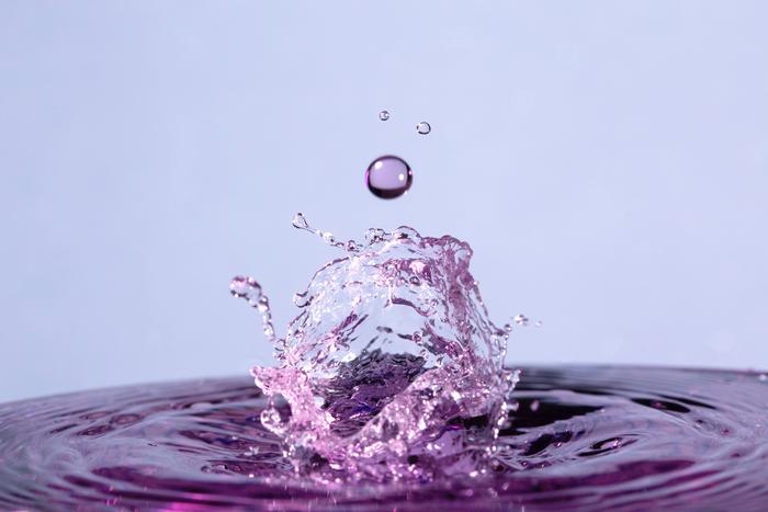 A droplet of water falls towards a turbulent water
